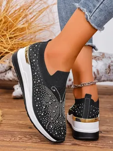 Close-up of black fly-knit wedge sneakers with sparkling rhinestone embellishments