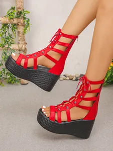 Nahaufnahme roter, ausgehöhlter High-Top-Keilsandalen mit Nietendetails und Schnürung vorne.