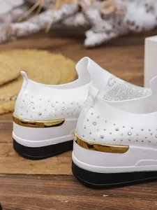 Detailed close-up showing the sparkling rhinestones and gold heel trim of these white knitted sneakers
