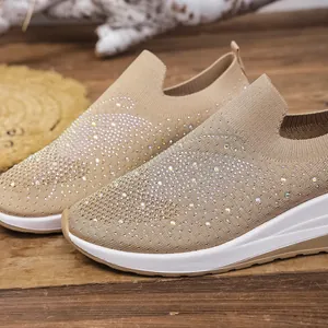 Close-up of beige knit wedge sneakers featuring sparkling rhinestone embellishments.