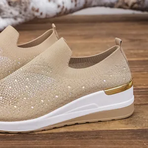 Close-up of beige fly-knit wedge sneakers featuring sparkling rhinestone embellishments