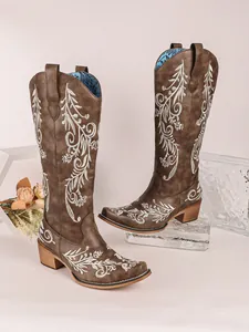 Close-up of brown embroidered cowboy boots with white floral patterns and V-mouth.