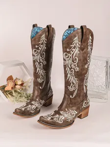 Detailed view of vintage brown Western boots featuring intricate white floral embroidery.
