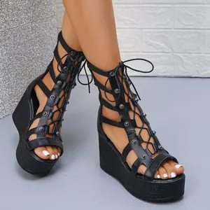 Nahaufnahme von schwarzen Gladiator-Keilsandalen zum Schnüren mit hohlem Design und Nieten