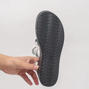 Detailansicht der wellenförmigen, rutschfesten schwarzen Laufsohle einer Retro-Flachsandal