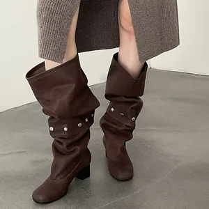 Detailed view of dark brown slouchy knee-high boots with silver studs and block heel