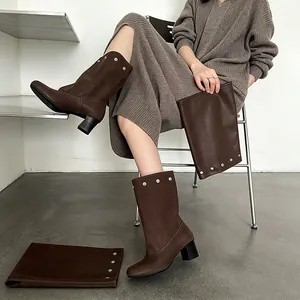 Stylish brown block heel pant-leg boots with silver rivet details worn by model