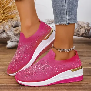 Fashionable pink rhinestone knit platform sneakers with wedge heel and gold detail.