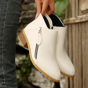 Detailed view of white leather ankle boots with pointed toe and double zipper design.