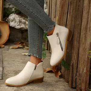 Close-up of white pointed toe block heel ankle boots with side zipper detail