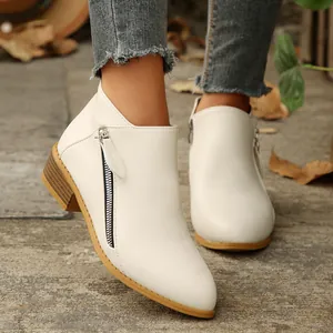 Close-up detail of white pointed-toe ankle boots featuring stylish double side zippers