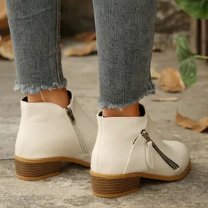 Detailed view of white pointed-toe ankle boots with double zippers and block heels.
