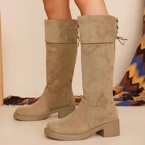 Detailed view of suede knee-high boots with chunky heel and lace-up back