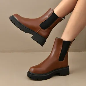Gros plan de bottines Chelsea brunes avec d'épaisses semelles crantées noires.
