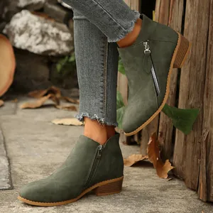 Detail view of dark green suede ankle boots with dual zippers and chunky heel