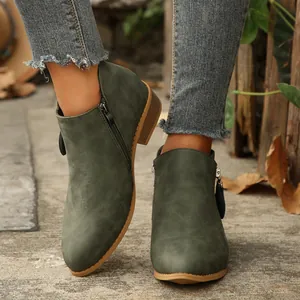 Detail view of stylish green pointed toe ankle boots with double side zippers and block heel.