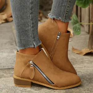 Detail view of brown suede ankle boots featuring double zippers and chunky heels