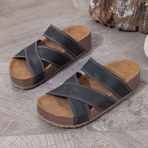Detailed macro view of black cross-strap platform slide sandals with white contrast stitching.