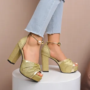Sandales à talons hauts dorées pailletées avec plateforme et bride perle à la cheville.