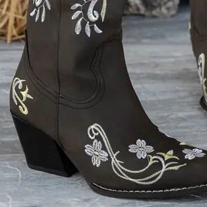 Detailaufnahme der eleganten Blumenstickerei an dunkelbraunen Overknee-Stiefeln mit Karree-Zehe