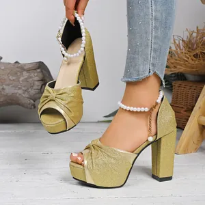 Détail élégant de sandales à talons hauts dorées pailletées avec nœud et perles