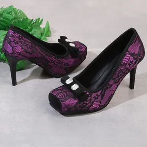 Detailaufnahme der lila Spitzen-High-Heels mit eleganter Schleife und Strasssteinen