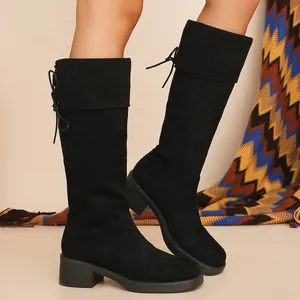 Detail of black suede knee-high boots with chunky heels and back lace-up closure