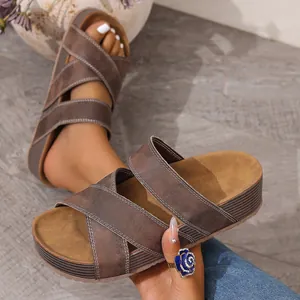 Close-up of brown platform slide sandals with crossover straps and white stitching
