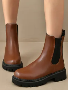 Bottines Chelsea marron élégantes avec semelles noires épaisses portées pour le détail