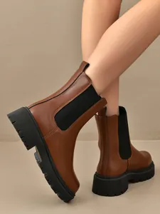 Gros plan sur des bottines Chelsea marron avec semelles crantées noires et élastique