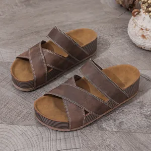 Detailed view of brown platform sandals with cross straps and white stitching.