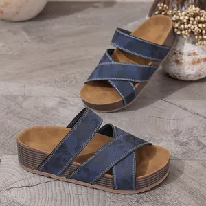 Close-up of blue platform sandals with cross-strap design on wooden floor