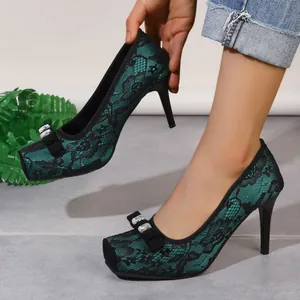 Nahaufnahme von grünen Spitzenpumps mit Strassschleife und Stiletto-Absatz