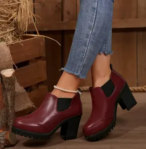 Side view of stylish burgundy high-heeled ankle boots with thick block heels and lug soles