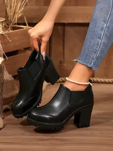 Close-up detail of black leather platform boots with thick heels shown on model