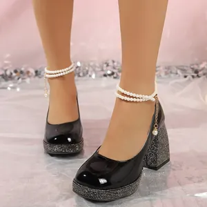 Close-up of black patent leather chunky heels with rhinestones and pearl ankle straps