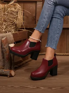 Detail view of women's wine red high heel platform ankle boots in rustic setting
