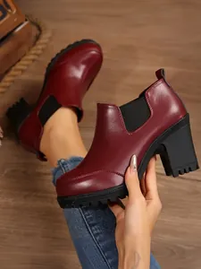 Close-up detail of burgundy leather ankle boots with chunky heels and platform soles