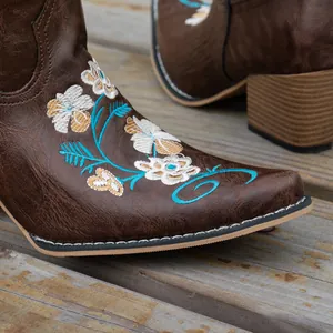 Detailed close-up of floral embroidery on brown leather western cowboy boots for women