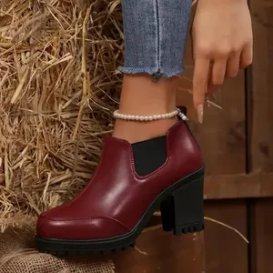 Close-up of wine red platform chunky heel ankle boot presented in a rustic hay background
