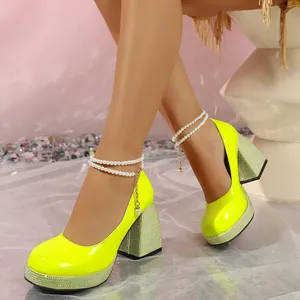 Close-up of neon yellow platform chunky heels with pearl anklets and rhinestone details