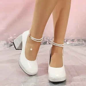 Detailed view of white patent leather block heels with rhinestone platform and pearl straps