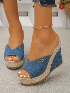 Detail view of denim fabric wedge sandals with woven straw platform and open toe