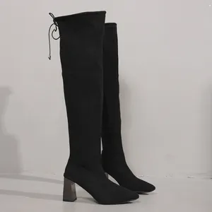Close-up of black suede over-the-knee boots with stylish block heels