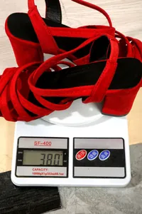 Detailed view of red chunky heel sandals weighing 380g on a professional digital scale.