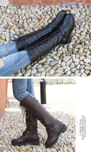Detail view of knee-high knight boots with lace-up front and buckle straps on pebbles.