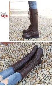 Detail of brown knee-high riding boots with lace-up front and metal buckle straps.