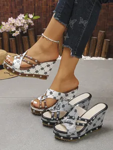 Detailansicht der Denim-Keilabsatzsandalen mit Nieten und Kleeblattmuster