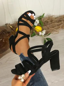 Close-up of black suede chunky heel sandals with crisscross straps and buckle detail