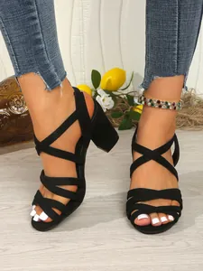 Detailed view of elegant black cross-strap chunky heel sandals with open toe on foot